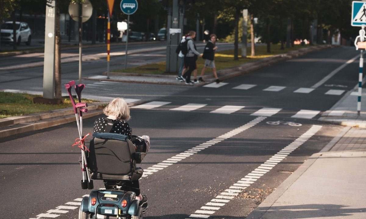 old lady crossing the road on a wheelchair