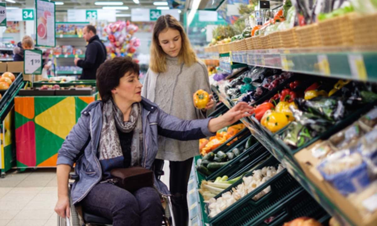 a daughter helping her mother for grocery who is on a wheel chair 